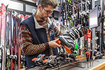 A man is working on a pair of atomic skis