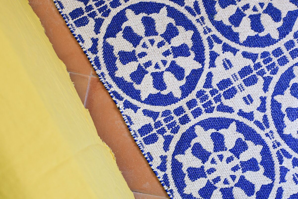 A blue and white rug is on a tiled floor