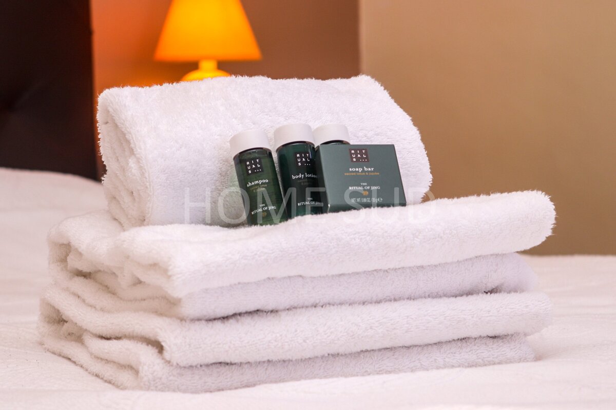 A stack of towels with bottles of ritual of ayurveda shampoo and body lotion