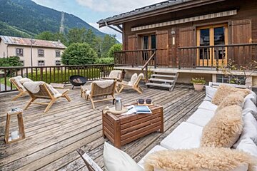 A wooden deck with a couch and chairs on it