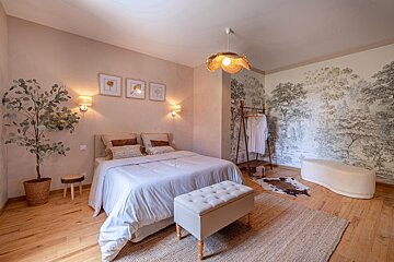 A bedroom with a large bed and a painting on the wall
