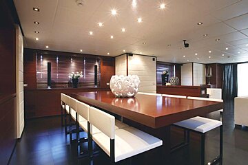 A dining room with a large wooden table and white chairs