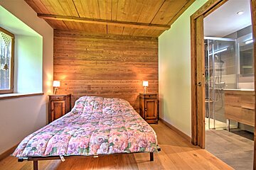 A bedroom with a floral comforter and a wooden wall