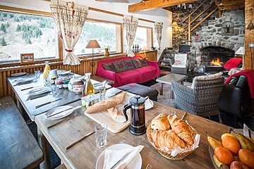 A long wooden table with plates and utensils on it in a living room