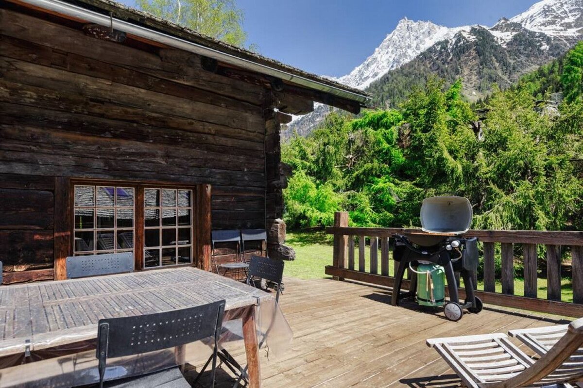 A wooden deck with a table and chairs and a grill