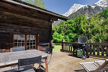 A wooden deck with a table and chairs and a grill