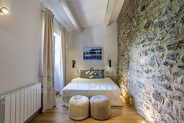 A bedroom with a stone wall and a bed