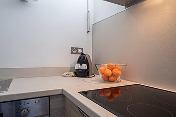 A krups coffee maker sits next to a bowl of oranges