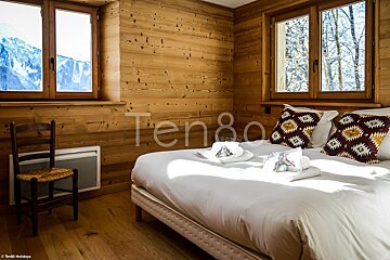 A bedroom with a bed and a chair and the word ten80 on the wall