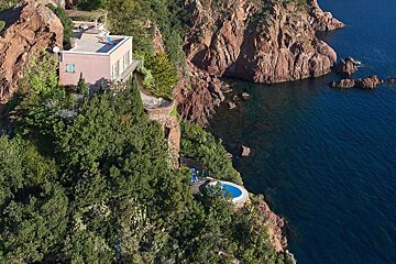 An aerial view of a house on a cliff overlooking the ocean