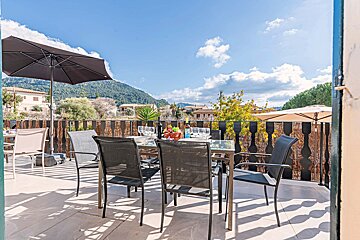 A table and chairs on a balcony with mountains in the background
