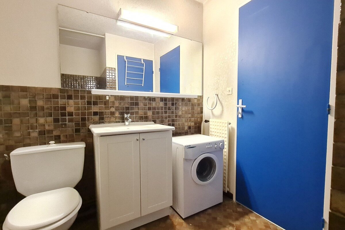 A bathroom with a washing machine and a toilet