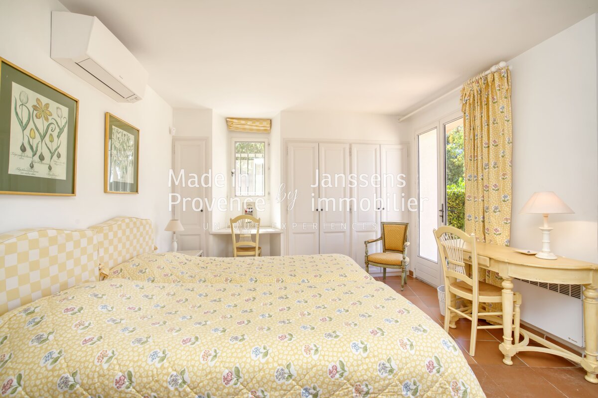 A bedroom with two beds and a desk that says janssens provence immobilier