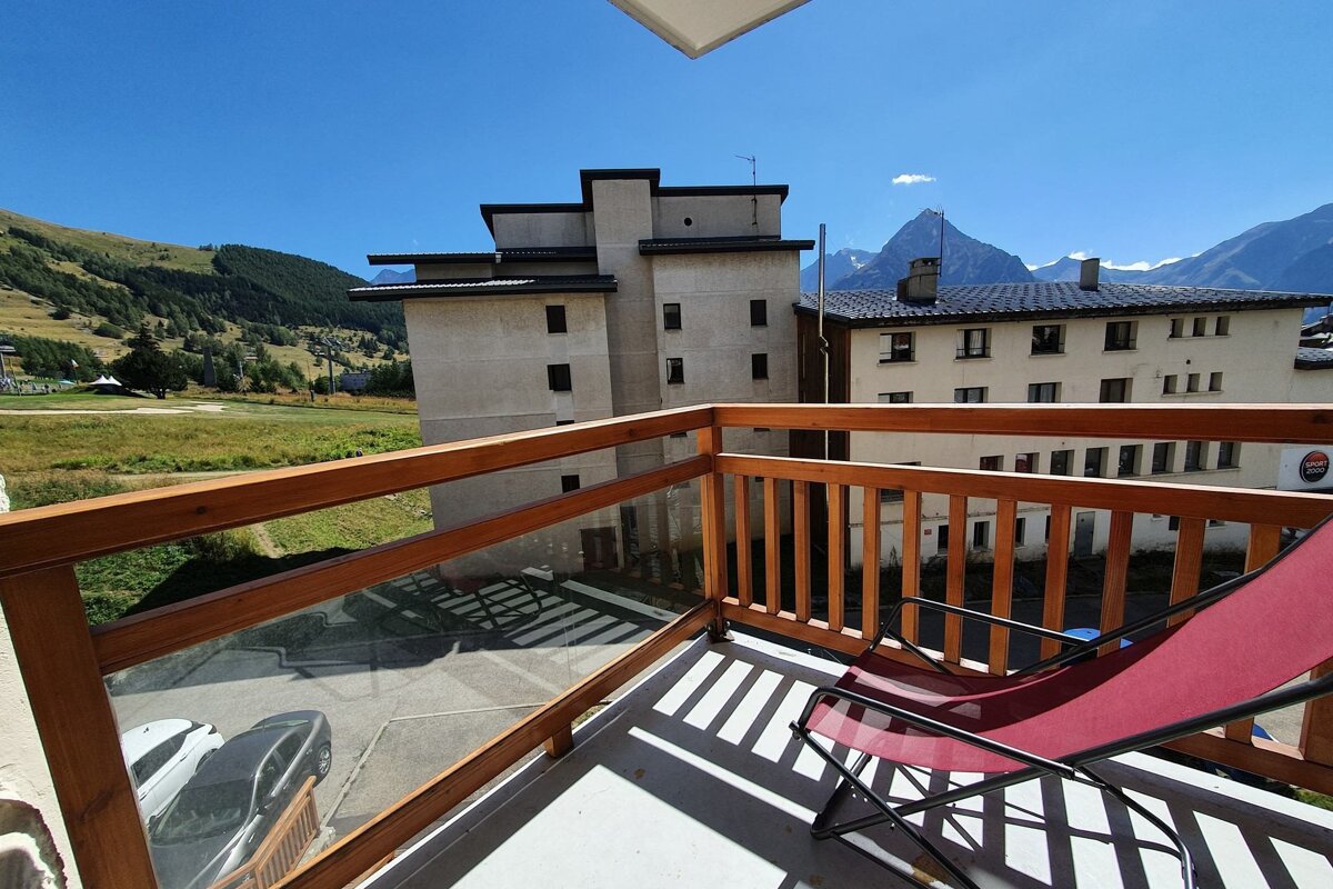 A balcony with a chair and mountains in the background