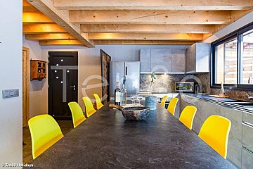 A kitchen with yellow chairs and a bottle of wine on the table