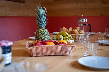 A pineapple sits on top of a basket of fruit on a table
