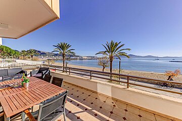 A balcony with a table and chairs overlooking the ocean