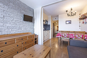 A living room with a table and chairs and a flat screen tv
