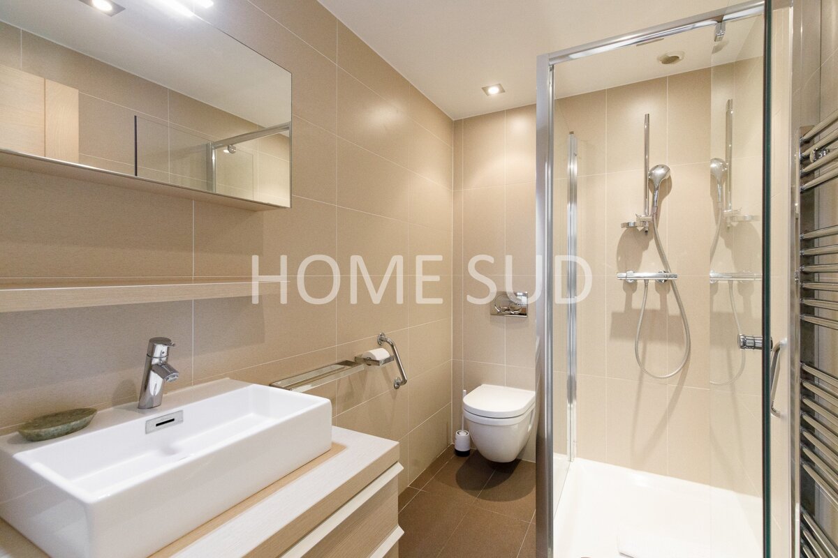 A bathroom with a sink toilet and shower has the word home on the wall