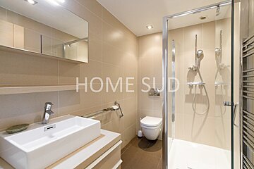 A bathroom with a sink toilet and shower has the word home on the wall