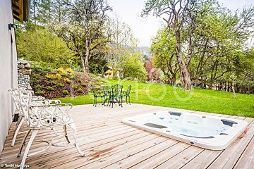 A hot tub sits on a wooden deck next to a table and chairs