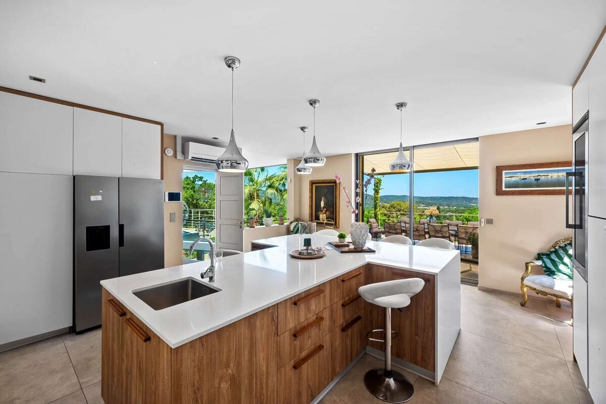 A kitchen with a large island and a stainless steel refrigerator