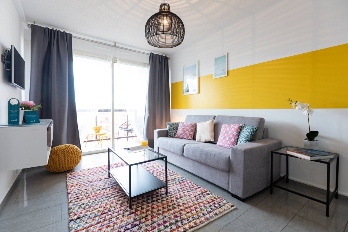 A living room with a gray couch and a yellow wall
