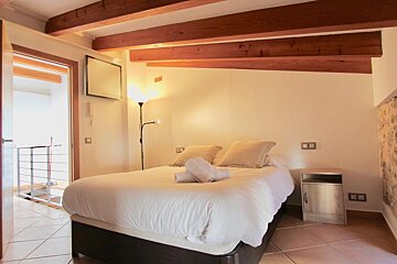 A bedroom with a large bed and a television on the wall