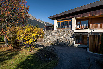 A large stone building with a balcony and mountains in the background