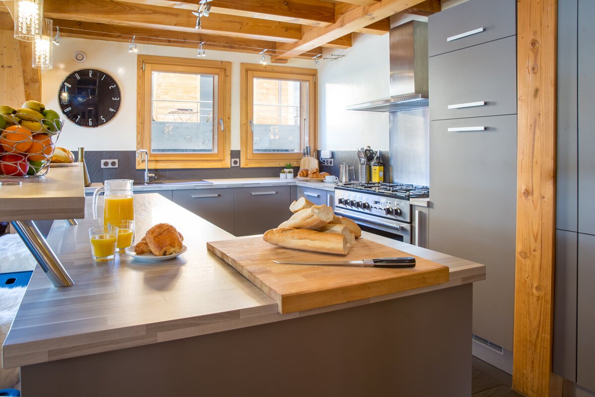 A kitchen with a clock on the wall and a cutting board with bread on it