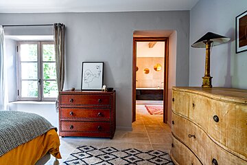 A bedroom with a dresser and a picture on the wall
