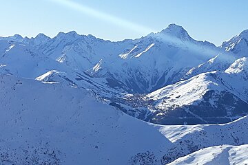 The sun shines through the snow covered mountains