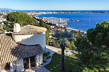 Scenic high-angle view of a coastal town and harbor with boats on a sunny day in Golfe-Juan, France.