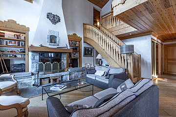 A living room with a fireplace and stairs leading up to the second floor