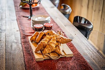 A wooden cutting board with croissants and jam on it