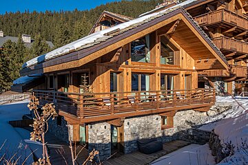 A large wooden house with a balcony in the snow