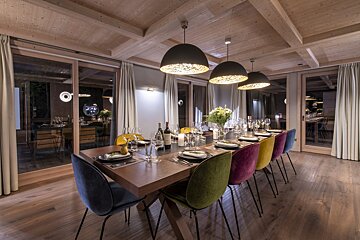 A dining room with a long table and colorful chairs
