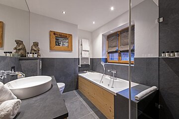 A bathroom with a tub a sink and a mirror