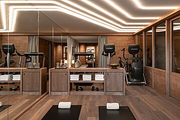 A modern, wood-paneled luxury gym featuring exercise equipment, mirrored walls, glowing ceiling lights, and yoga mats with towels.