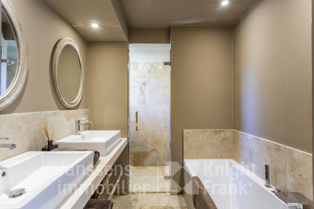 A bathroom with two sinks and a bathtub with knight frank written on the wall