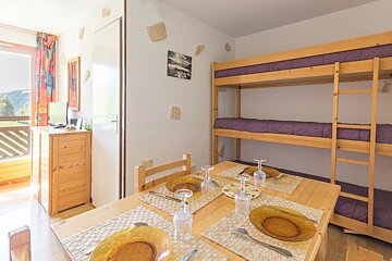 A wooden table with plates and glasses on it in a room with bunk beds