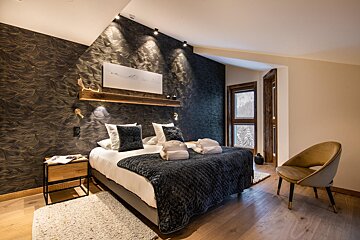 A bedroom with a large bed and a chair