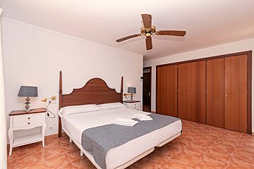A bedroom with a bed and a ceiling fan