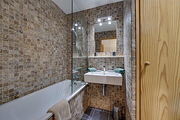A bathroom with a tub a sink and a mirror