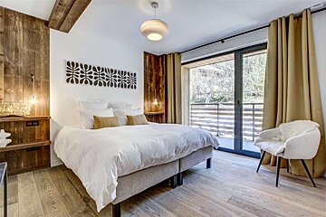 A bedroom with a large bed and a chair