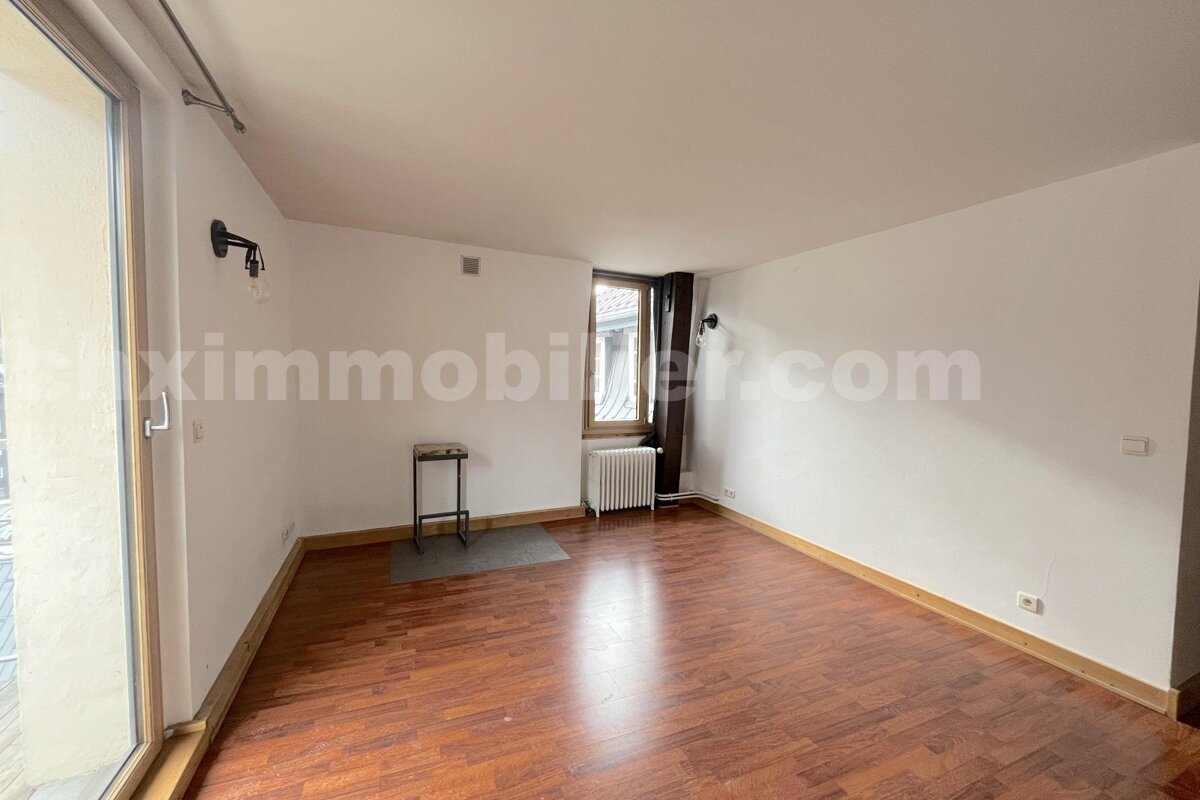 Spacious, empty room with warm wood flooring, white walls, a large glass door, and a window with a radiator.
