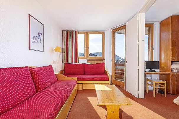 A living room with a red couch and a wooden table