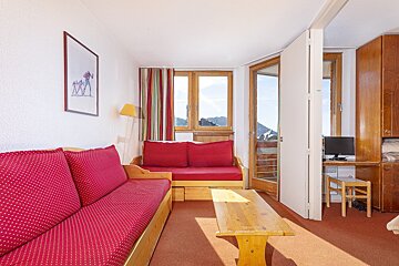 A living room with a red couch and a wooden table