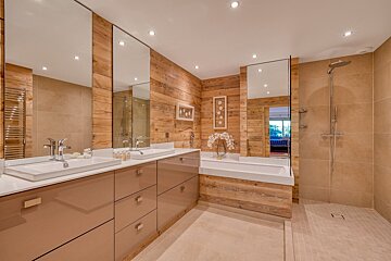 Modern bathroom with wood walls, double vanity, large mirrors, built-in tub, and walk-in shower.