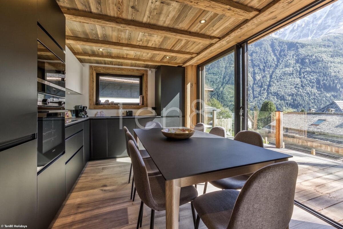 A kitchen with a table and chairs and a view of the mountains